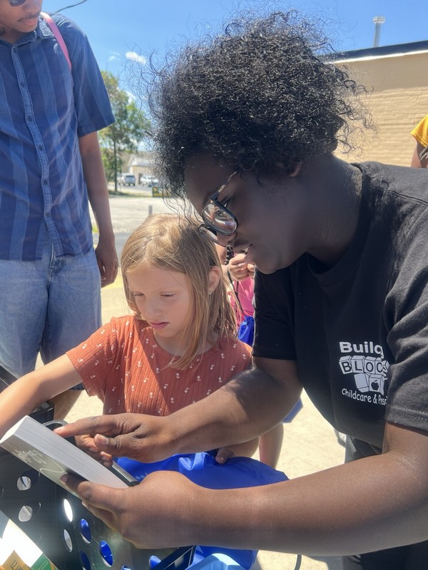 Young people exploring books at a Guided Grace FYS community giveaway